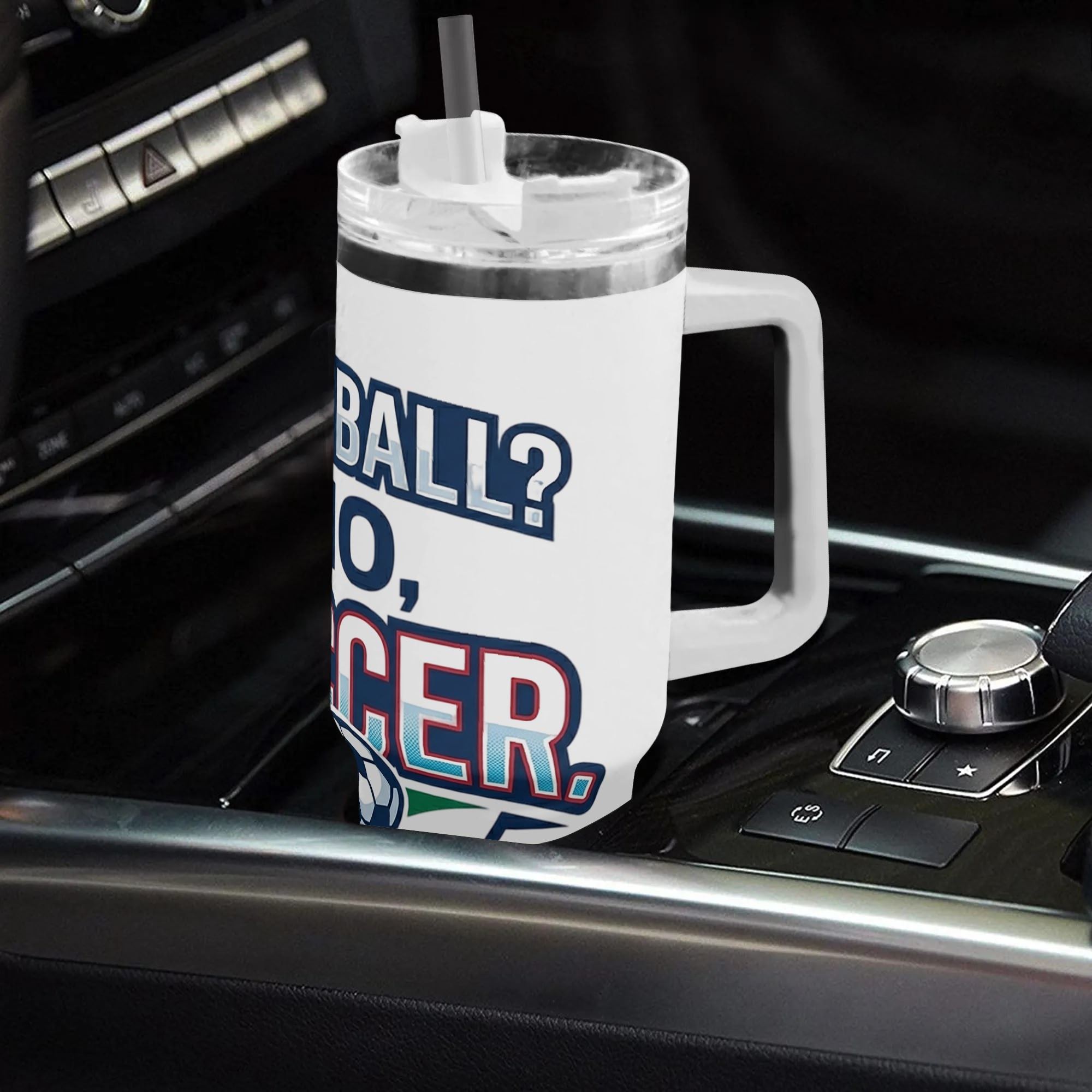 White 40oz handled insulated tumbler with funny "Football? No, Soccer" soccer-themed print placed on car gear shift console, 2026 World Cup fan stainless steel travel mug for driving
