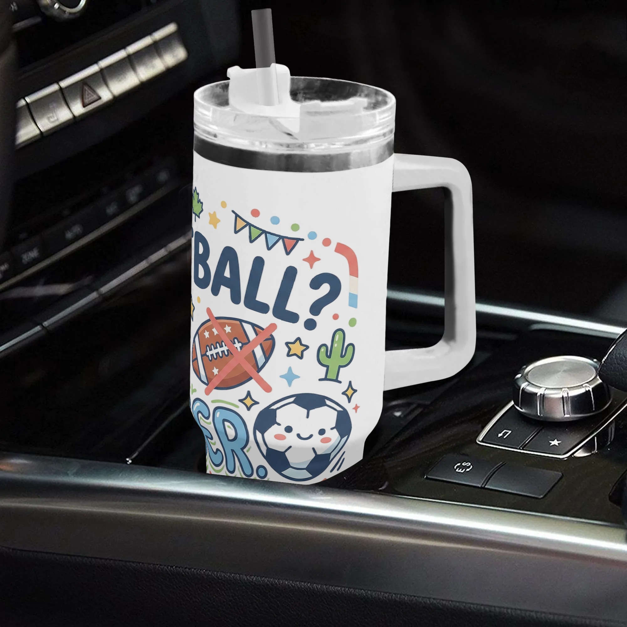 White 40oz handled tumbler with cute "Football No Soccer" cartoon doodle print placed in car gear shift console, soccer fan insulated stainless steel travel mug for driving
