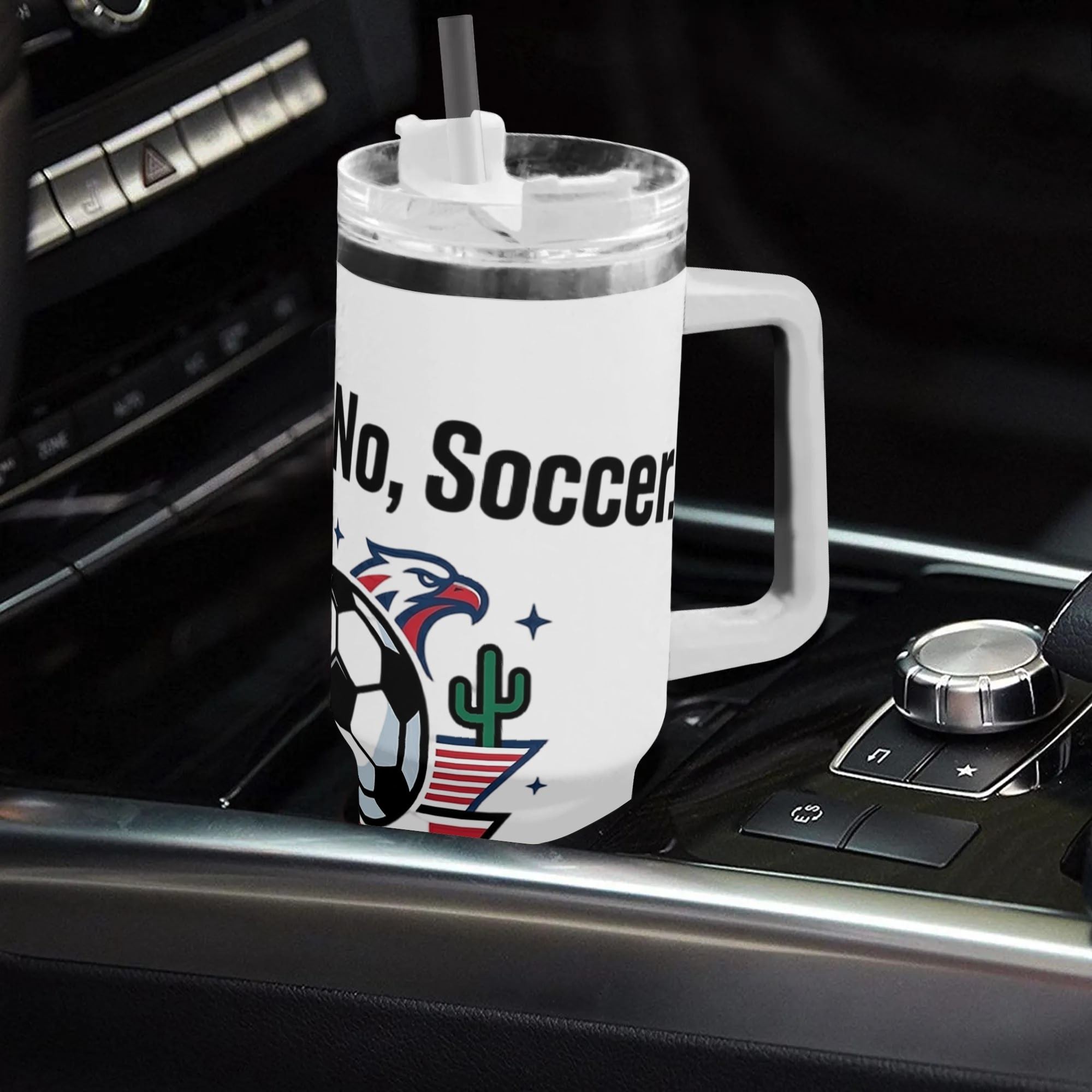 White 40oz handled insulated tumbler printed with Football? No, Soccer eagle shield patriotic graphic, placed on car gear shift console, 2026 World Cup fan stainless steel travel mug for driving