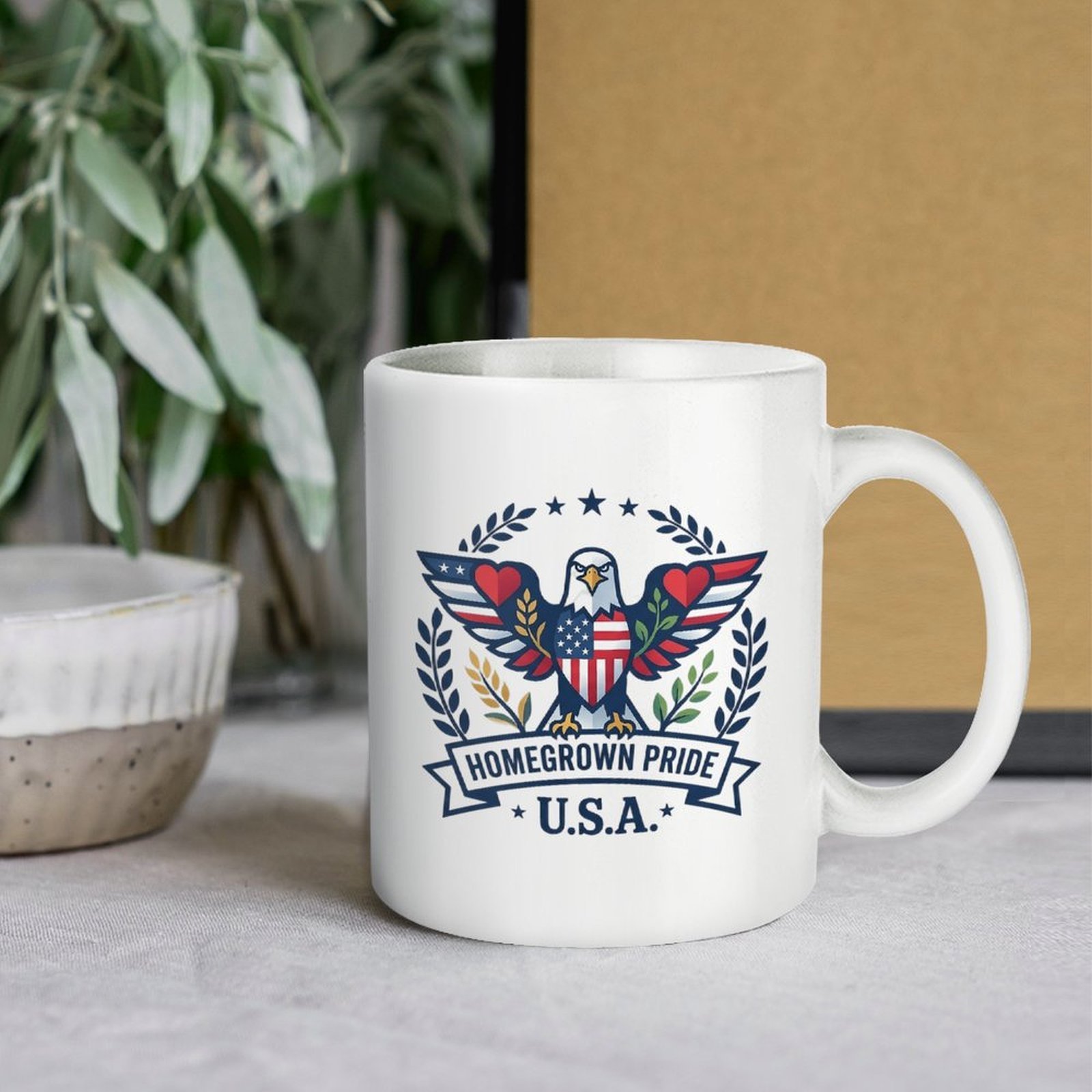 Lifestyle interior shot: Homegrown Pride eagle patriotic mug displayed on warm wooden table with cotton sprig background for home and office desk decor
