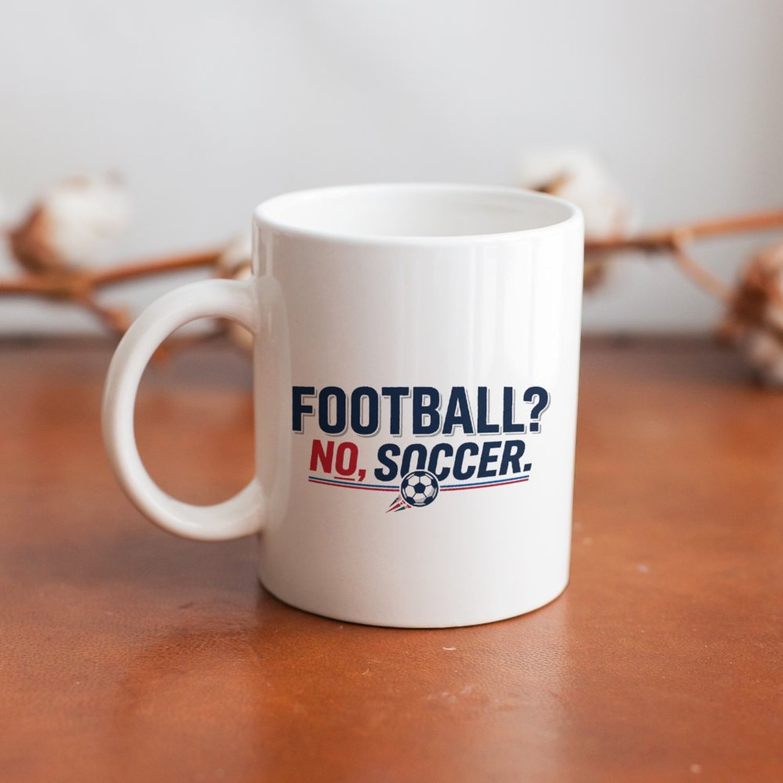 Close-up shot of the mug placed on a warm wooden tabletop, displaying the trendy soccer slogan design in soft natural lighting.
