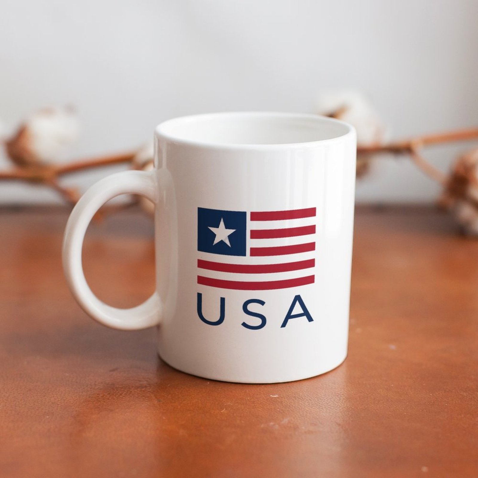 The mug displayed on a wooden table, highlighting the simple patriotic print under soft natural light.
