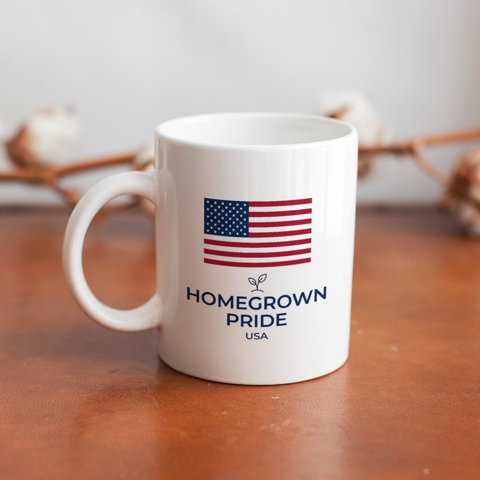 Lifestyle photo of the Homegrown Pride USA flag mug placed on warm wooden table with cotton decor background for home display
