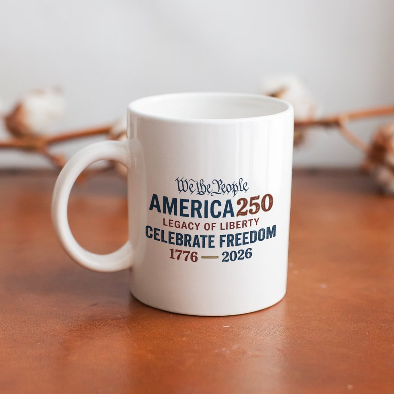 Antique We The People America 250 constitution text graphic white coffee mug resting on rustic wooden table, vintage USA 250th patriotic farmhouse decor drinkware