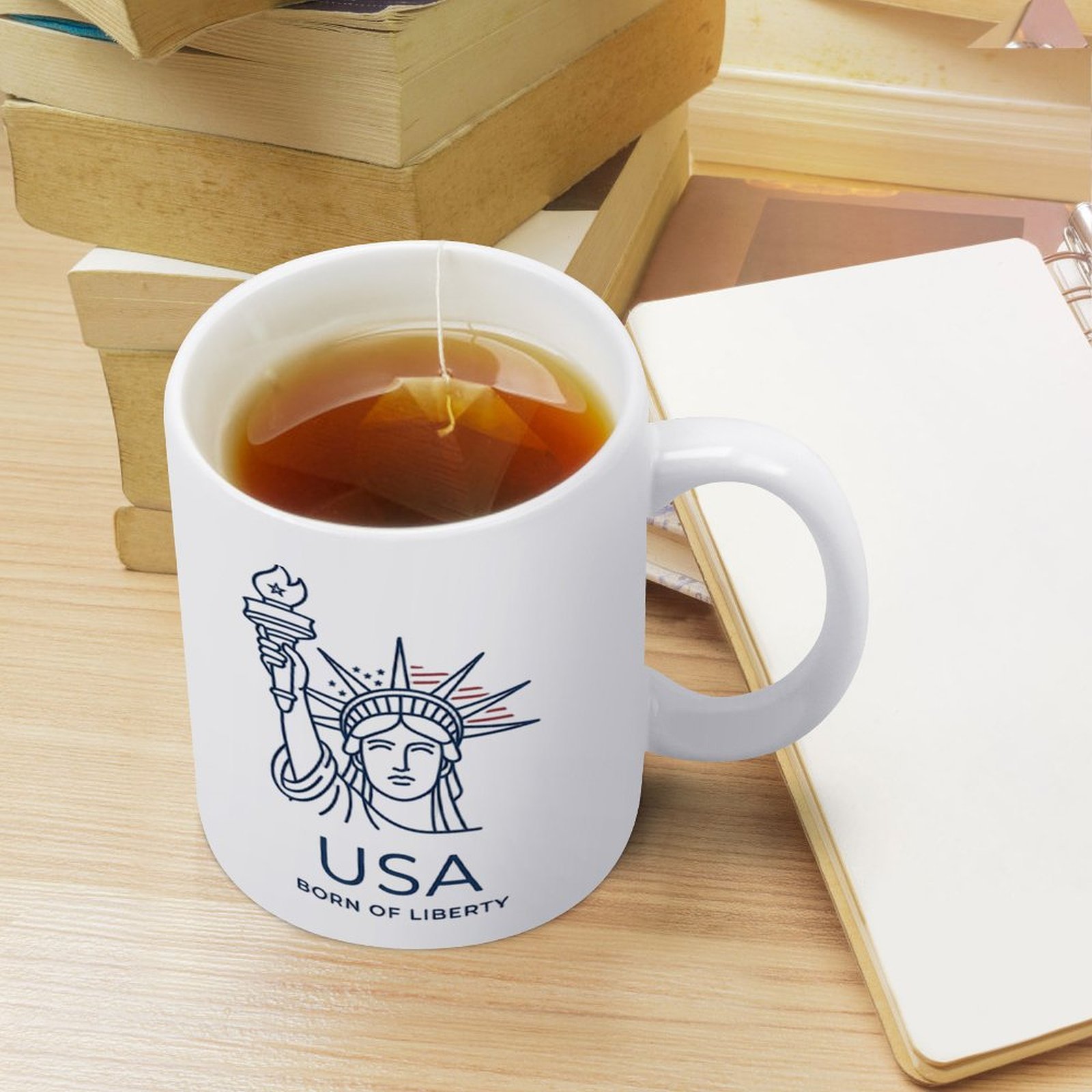 Lifestyle interior shot: Statue of Liberty patriotic mug placed on warm wooden table with cotton decor for home & office desk display