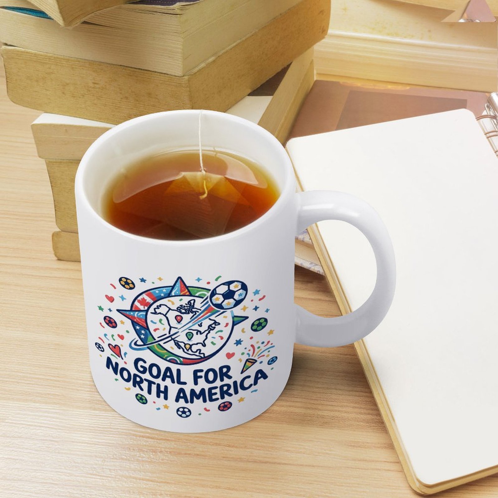 Lifestyle shot of the mug filled with tea, sitting on a desk with books and a notebook, showing everyday use