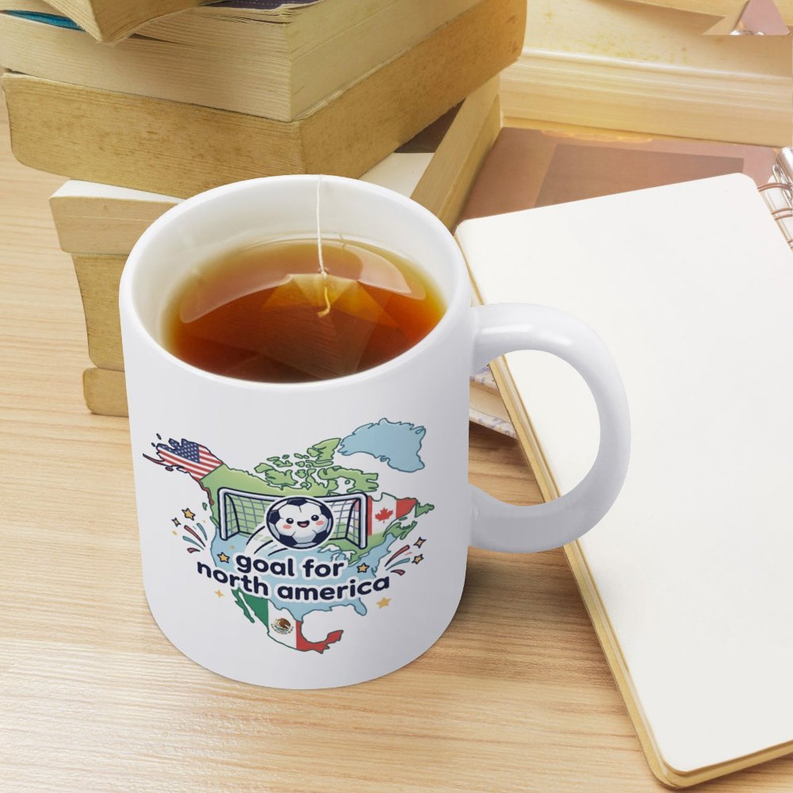 Lifestyle shot of the mug filled with tea, sitting on a desk with books and a notebook, showing everyday use